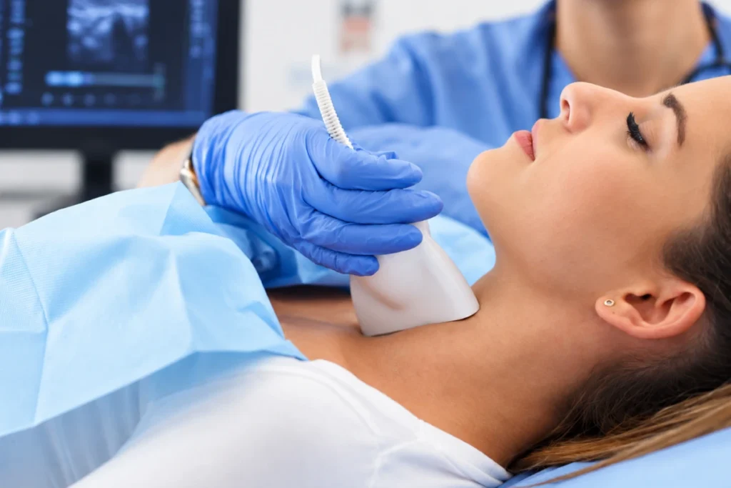 A patient undergoing a thyroid ultrasound examination on her neck to evaluate thyroid nodules and tissue characteristics.