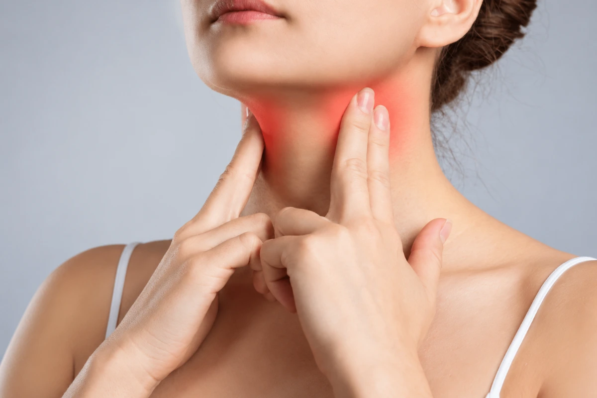 Close-up of a woman touching her throat area to check for a neck lump or thyroid nodule swelling.