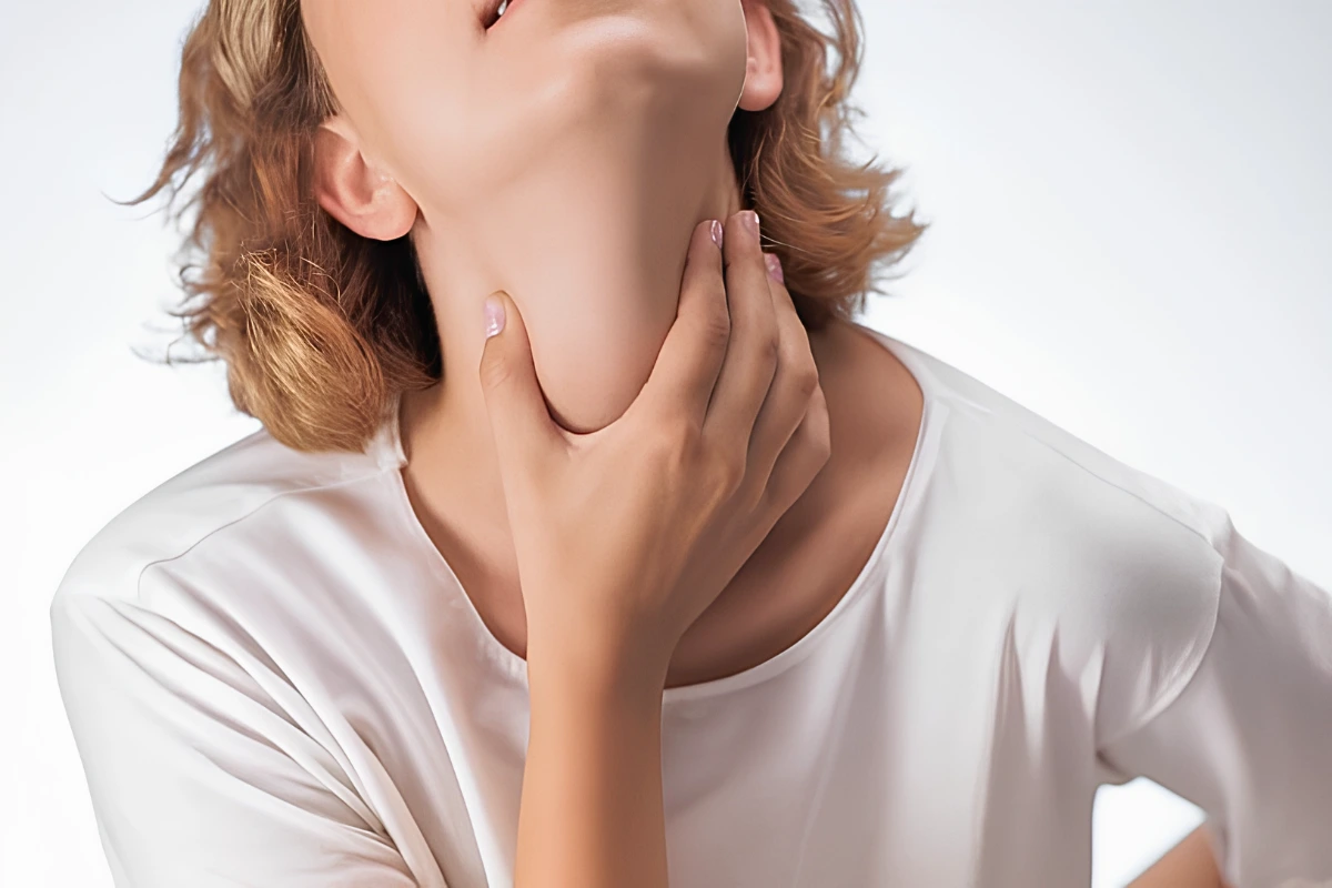 Close-up of a woman holding her neck and throat area in discomfort due to vocal strain, laryngitis, or voice problems.